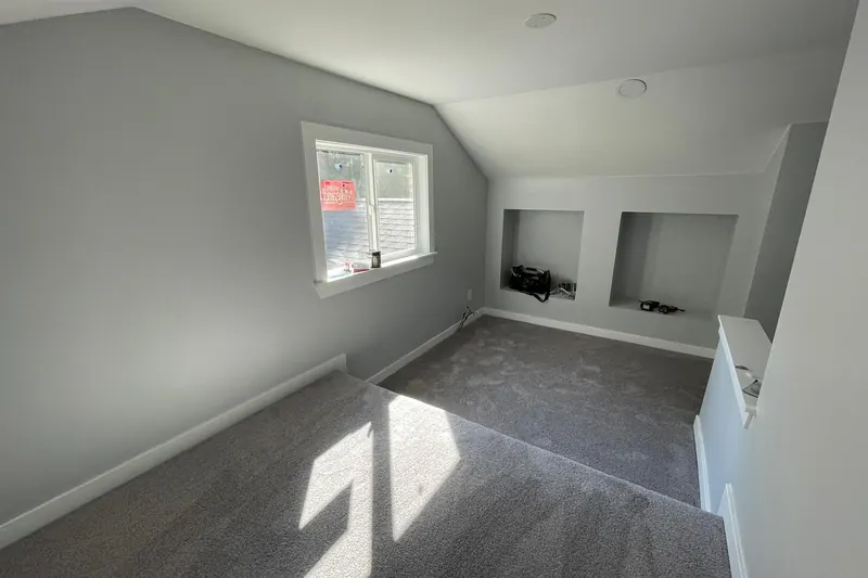 Finished attic conversion in Kirkland, WA with a gable window, gray carpet, sloped ceilings and built in wall niches