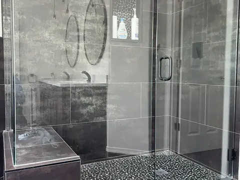 Glass shower with a tiled bench and a pebble floor in an Issaquah, WA bathroom