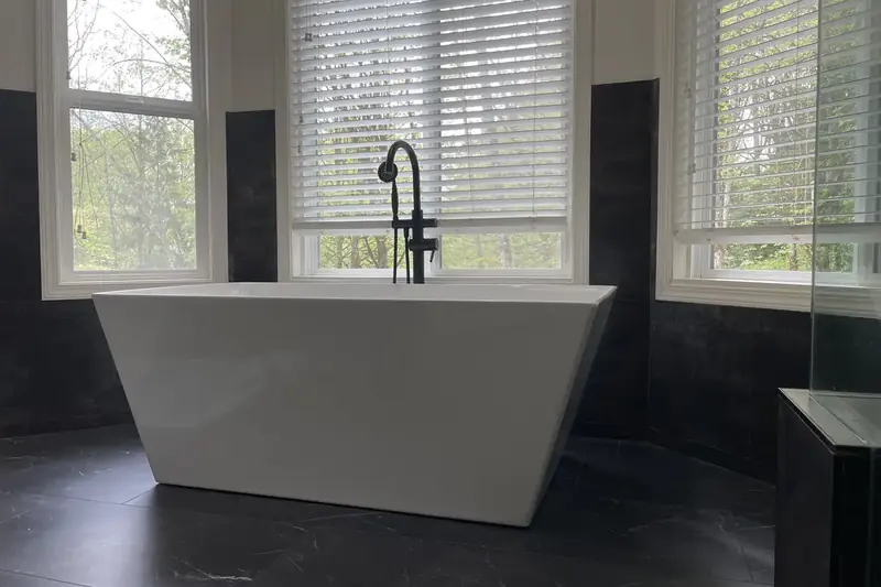 Freestanding tub with a black floor-mounted filler in a window bay of a remodeled Issaquah, WA bathroom