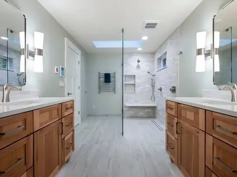 Two wood vanities facing each other with an open walk-in shower between them in a Redmond, WA bathroom