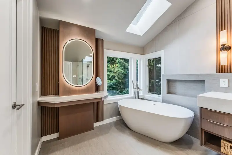 Remodeled master bathroom in Redmond, WA with a freestanding tub, a walnut slat wall and a lit oval mirror