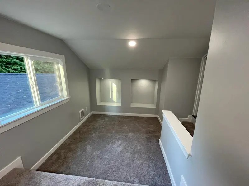 Two built-in niches under a sloped ceiling with a window on the side wall