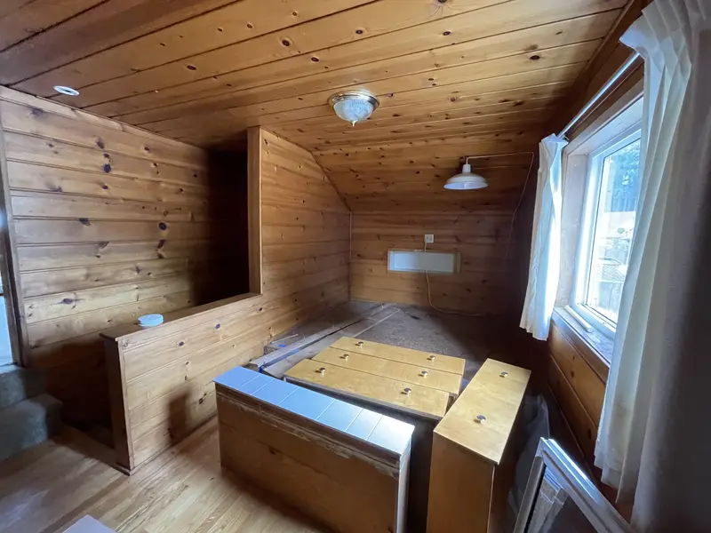 Pine-paneled attic with built-in wooden bunks and cabinets under the sloped ceiling
