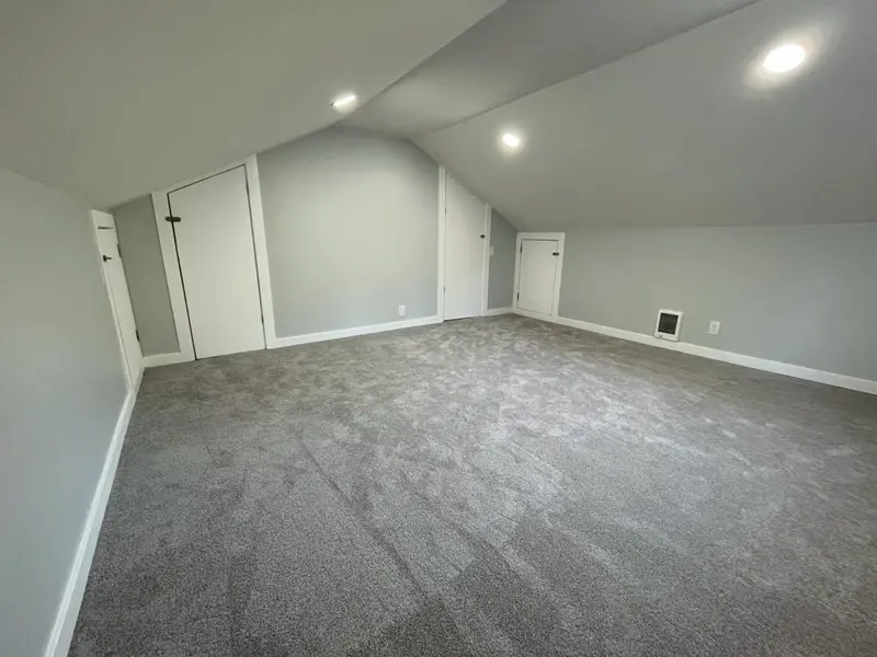 Attic room with closet doors set into the knee wall and recessed ceiling lights