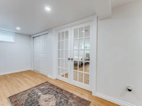 Finished basement hallway in Seattle, WA with glass French doors, a closet and light plank flooring