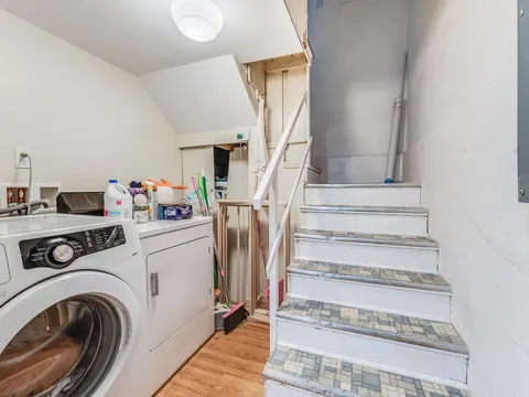 Basement laundry area in Seattle, WA with a washer, a dryer and the stairs up to the main floor