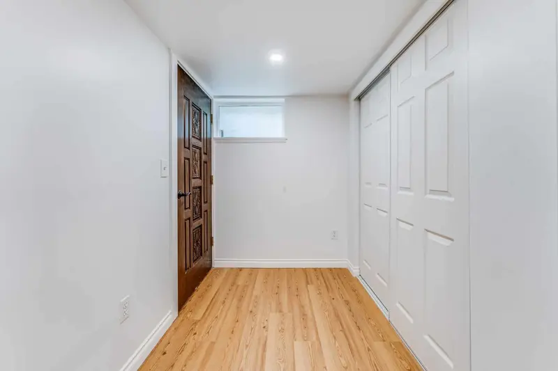 Basement hall with white closet doors and a dark wood exterior door at the end