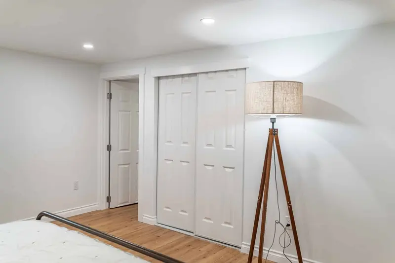 White bifold closet doors on the bedroom wall beside a floor lamp