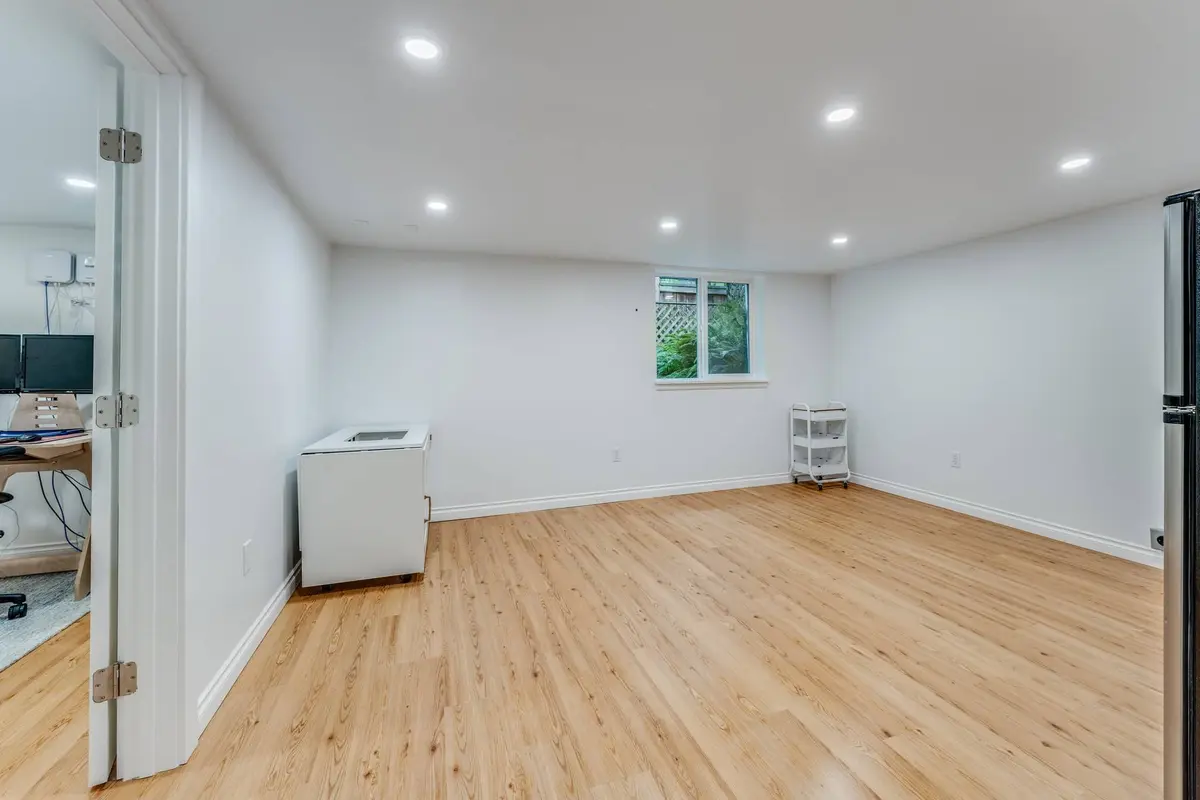 Finished basement room with a light oak-look plank floor, white walls and recessed lights