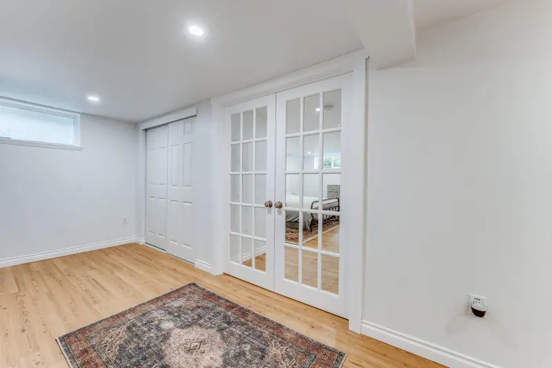 Glass French doors closed at the end of a room with a rug on the plank floor
