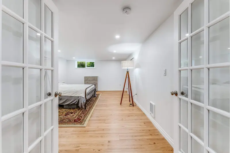 View through open glass-paned French doors into the basement bedroom