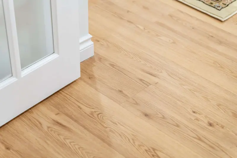 Close view of the light oak-look plank floor meeting a white glass-paned door