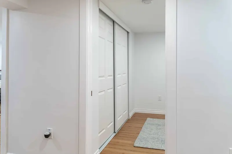 White sliding closet doors in a short basement hall with a light plank floor