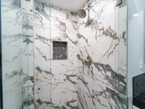 Frameless glass shower with a tiled niche and marble look porcelain walls in Bellevue, WA