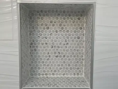 Recessed shower niche lined with marble hexagon mosaic in a white wave tile wall in Bothell, WA