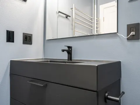 Black vanity with an integrated sink and a matte black faucet below a wide mirror in a bathroom in Everett, WA