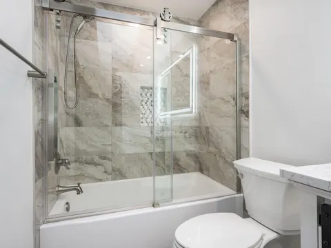 Tub with a sliding glass door and marble look wall tile in a bathroom in Tulalip Bay, WA