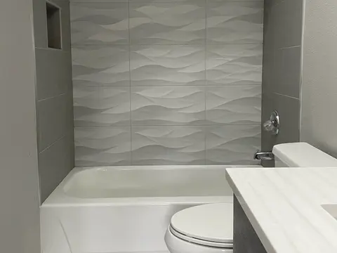 Bathtub with a sculpted wave tile wall, a tiled niche and a white vanity top in Kirkland, WA