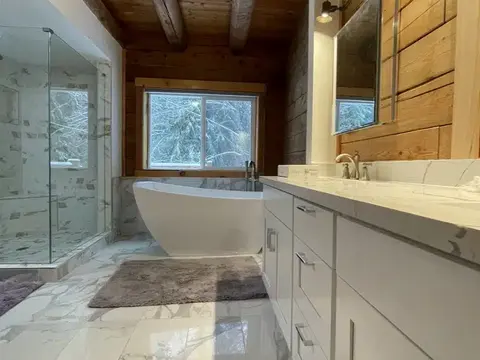 Master bathroom in Monroe, WA under a cedar beam ceiling with a freestanding tub, a glass shower and a white vanity with a quartz top