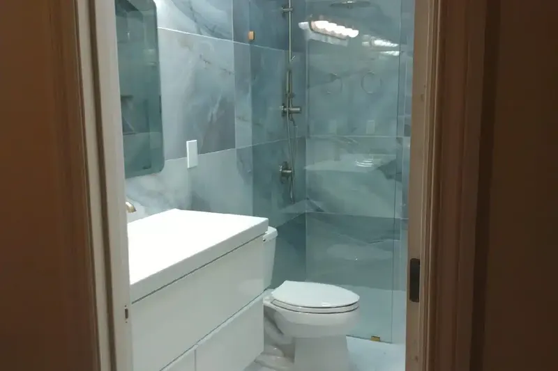 Remodeled bathroom in Monroe, WA seen from the doorway: a frameless glass shower with a rain head, gray marble look wall tile and a floating white vanity