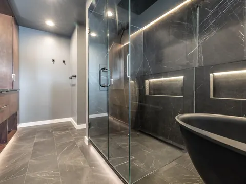 Black marble look shower with lit niches and a black freestanding tub in Redmond, WA
