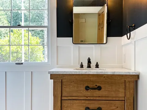 Powder room in Sammamish, WA with navy walls, white board and batten wainscot and a rustic wood vanity with a marble top