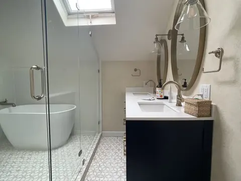 Primary bathroom with a freestanding tub, glass shower and navy vanity in Seattle, WA