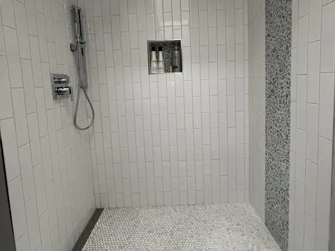 Walk in shower with white vertical tile, a pebble mosaic stripe and a recessed niche in Seattle, WA