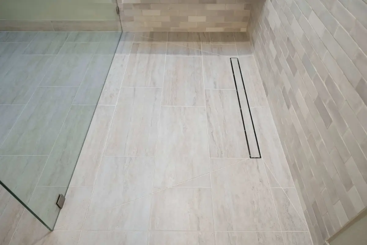 Linear drain along the shower wall with wood-look tile running in and no curb