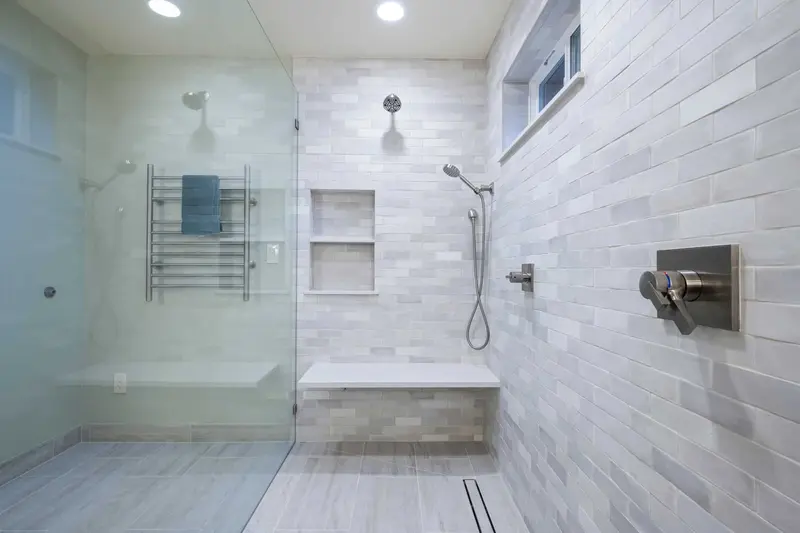 Inside the walk-in shower with a handheld on a bar, a niche, the bench and the glass panel