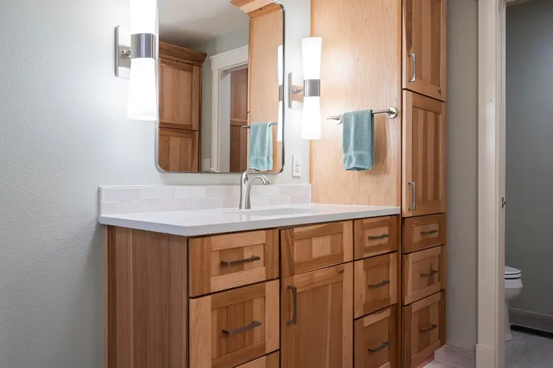 Wood shaker vanity with a white top, tall cabinet, sconces and a mirror