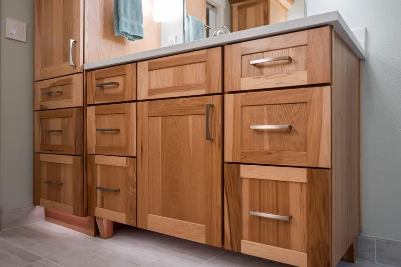 Bank of wood shaker drawers and doors with brushed pulls on raised feet
