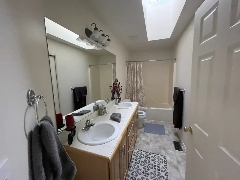 Long view of the old bathroom from the door, with the skylight, oak vanity and tub curtain