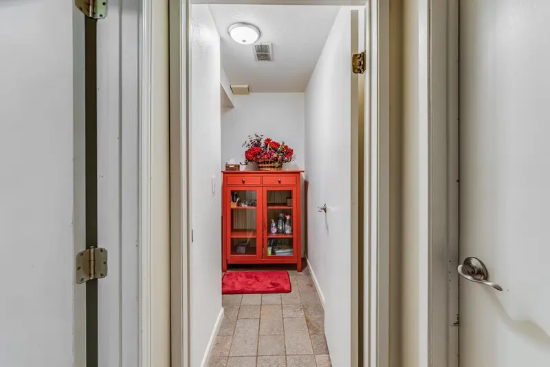 Narrow hallway leading to the bathroom before the remodel, with a red cabinet at the far end