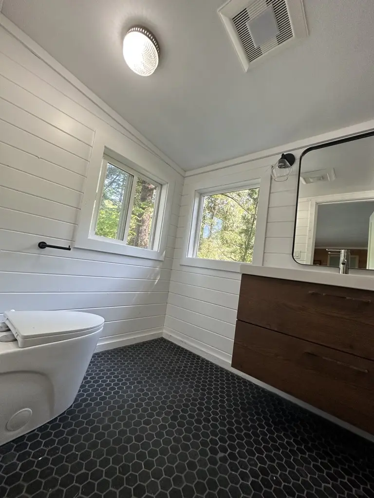 One-piece toilet on the window wall with white shiplap and a black towel bar