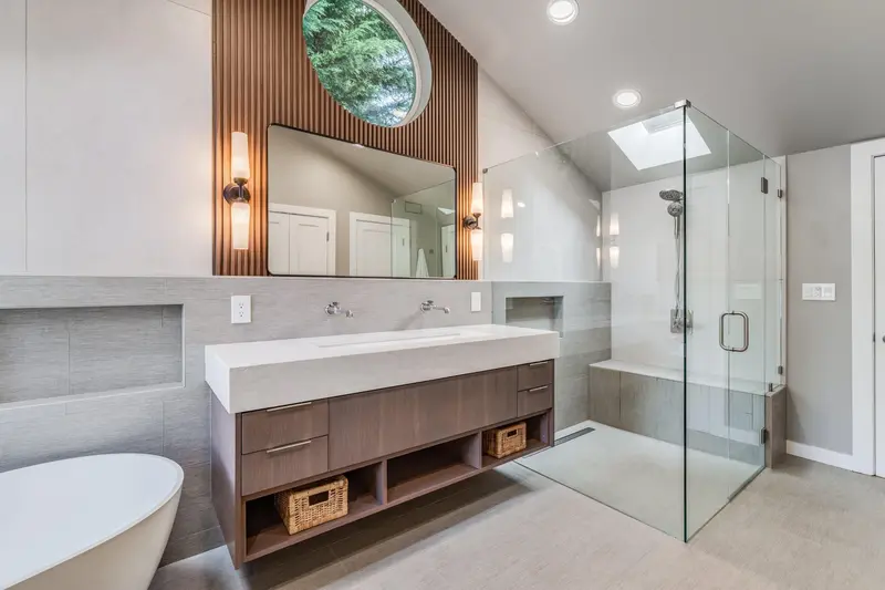Floating wood double vanity with a white trough sink under a wood slat wall, beside a glass walk-in shower
