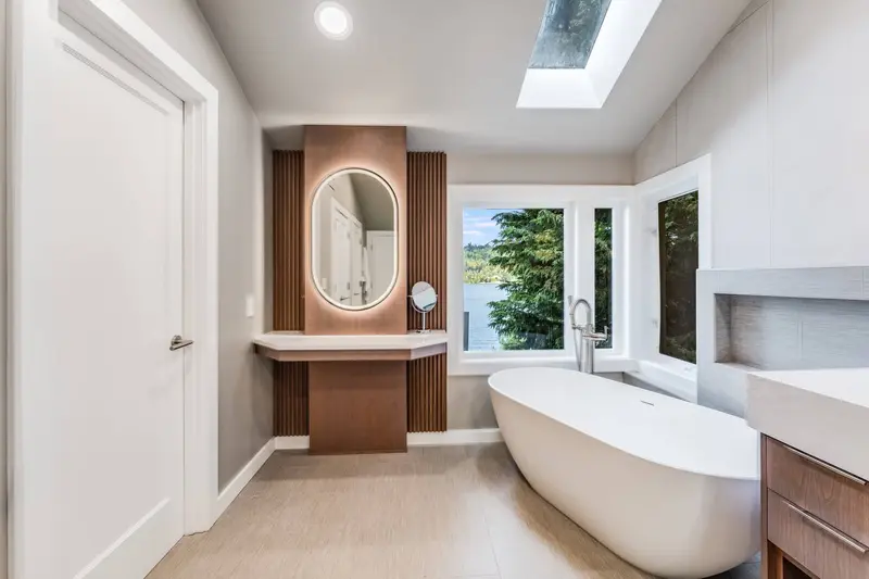 Freestanding tub with a floor-mounted filler under tall windows looking out to trees
