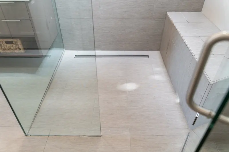 Frameless glass shower with a linear drain along the large-format floor tile