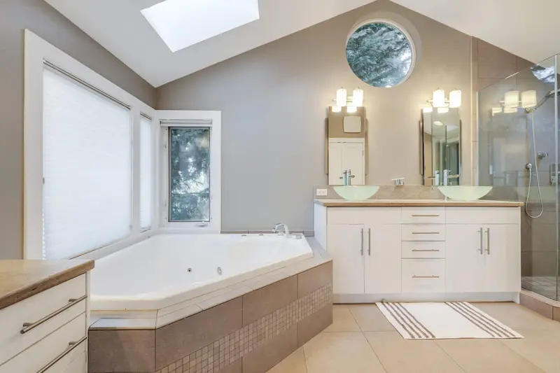 Master bathroom before the remodel with a tiled corner jetted tub, a white vanity and a glass shower