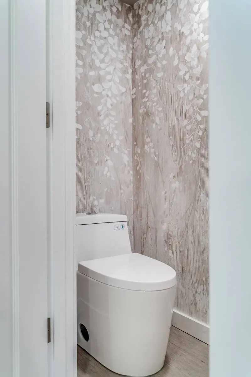 Separate toilet room with a mosaic accent wall and a white toilet