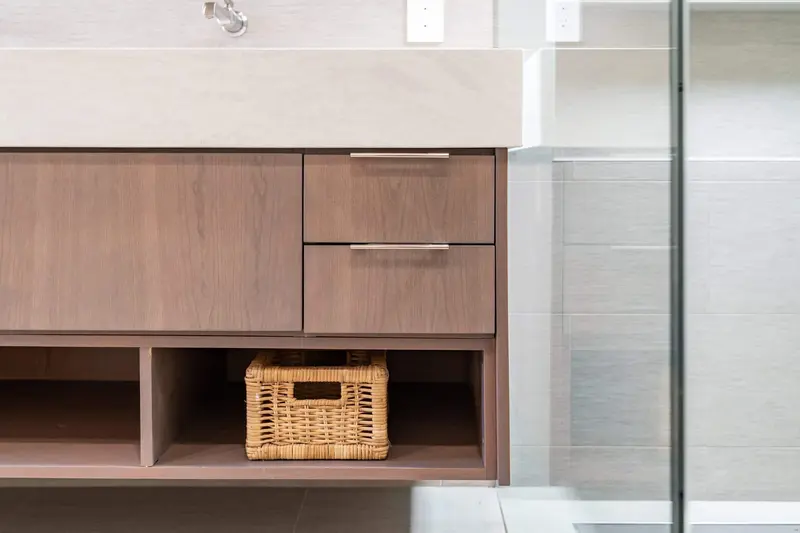 Floating wood vanity drawers above an open shelf with woven baskets