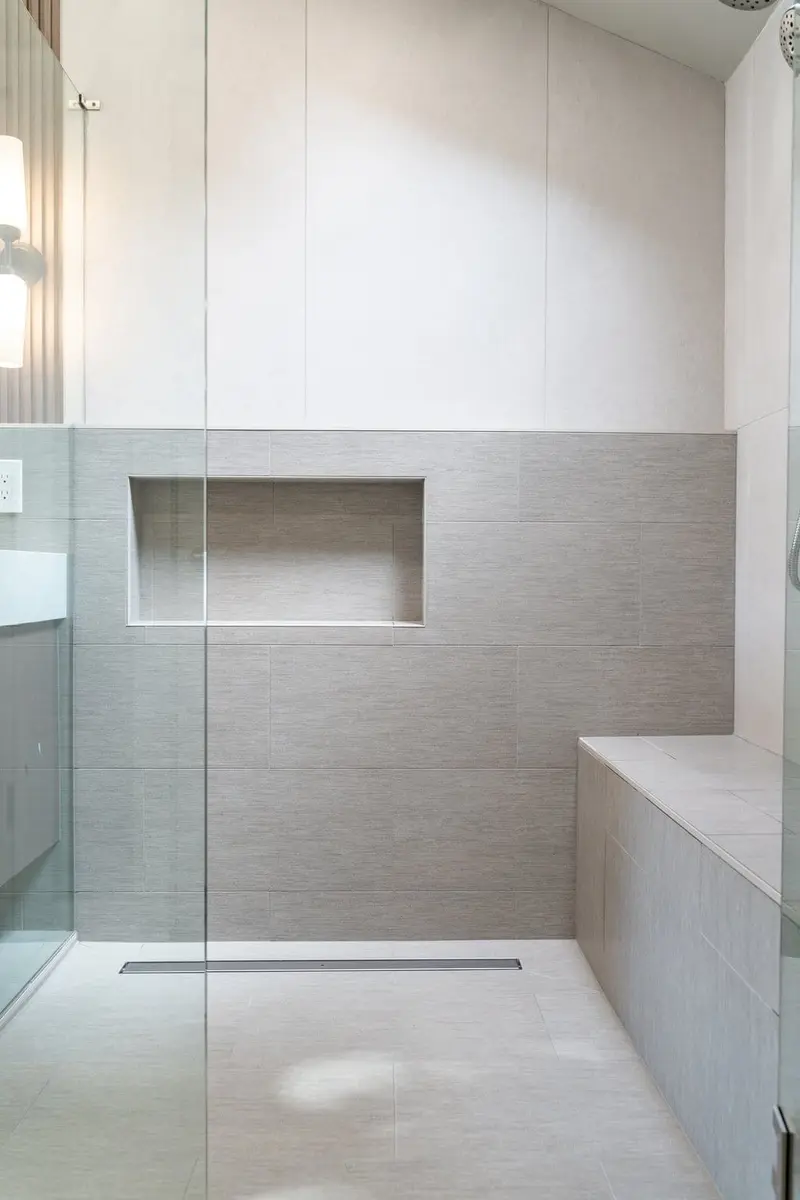 Walk-in shower with large-format tile, a long niche, a built-in bench and a linear drain