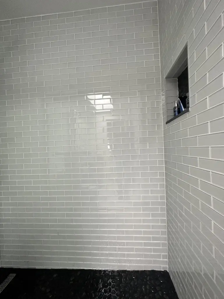 Shower corner with a tiled niche and a small window set into the subway tile wall