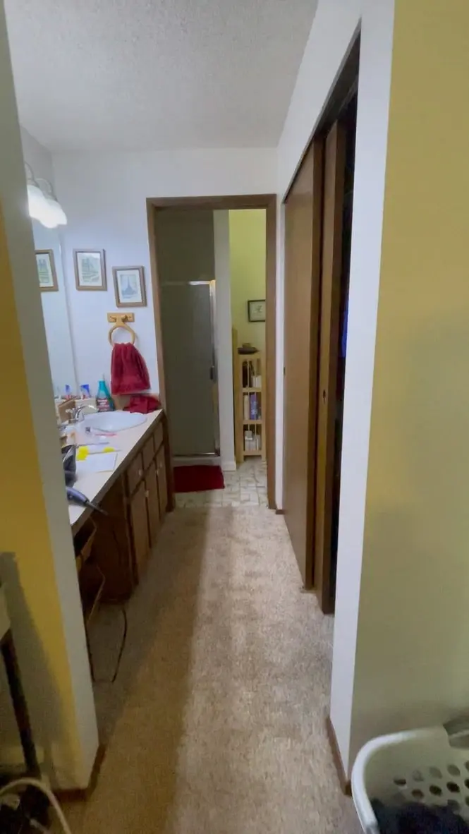 Narrow carpeted vanity hall in the primary bathroom before the remodel, with closet doors on the right