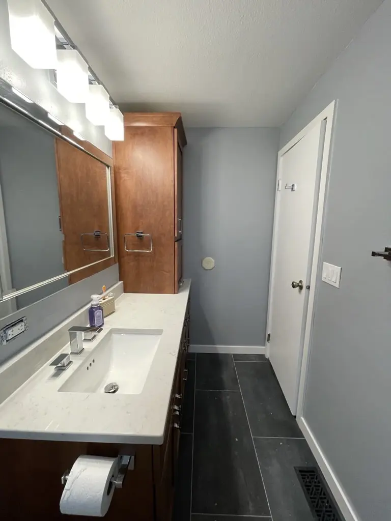 Light vanity top with an undermount sink, a toilet beyond and a white door on dark floor tile