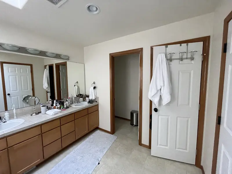 Old vanity wall with two sinks and the doors to the toilet room and the closet