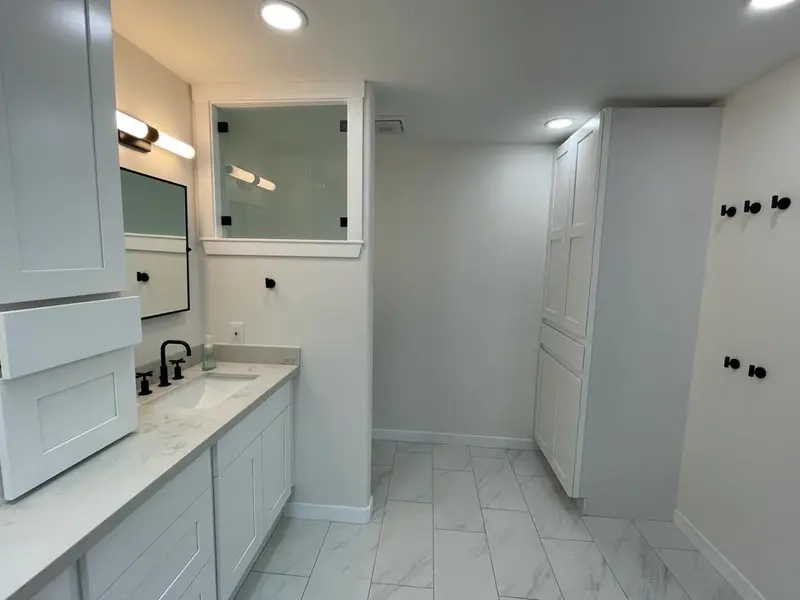 White shaker vanity with a tall upper cabinet, a mirrored cabinet and a full height linen tower
