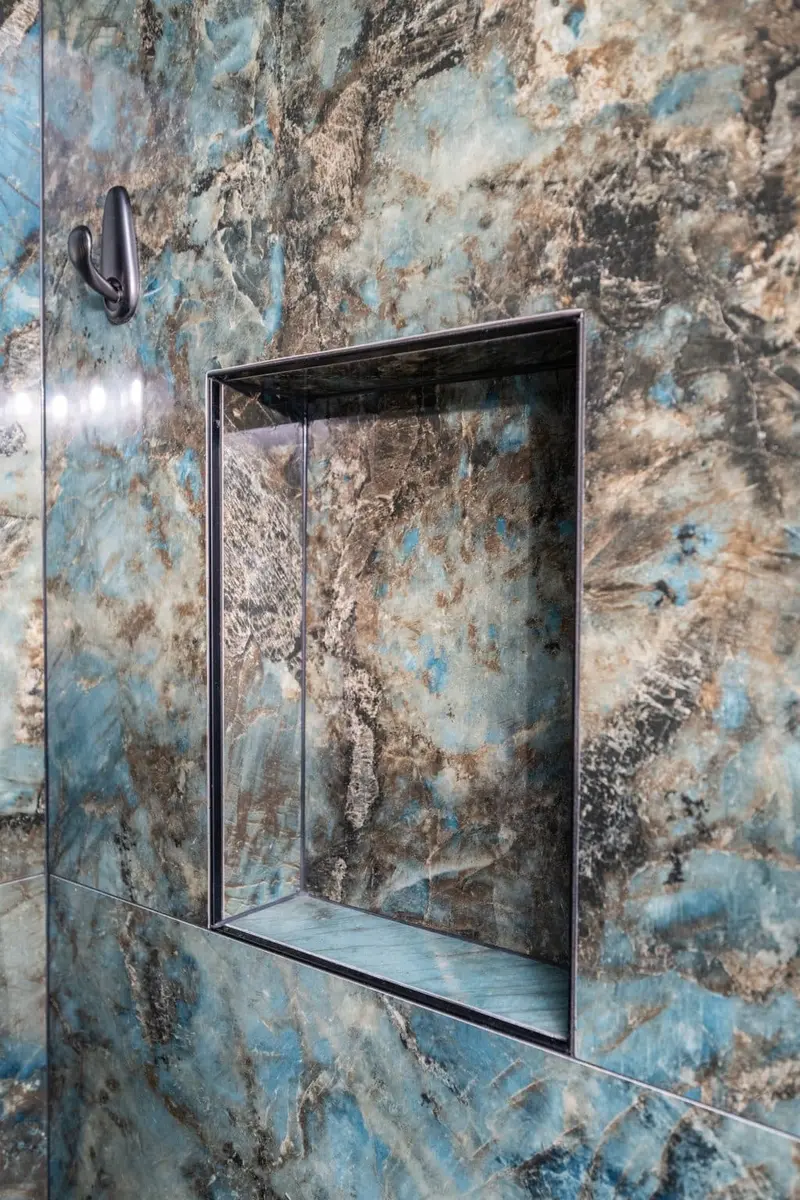 Recessed shower niche finished in the same stone-look panel and edged in black trim