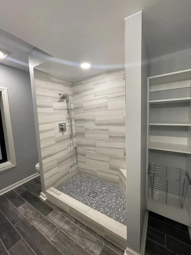 Shower entry with a tiled curb beside a built-in white shelving unit