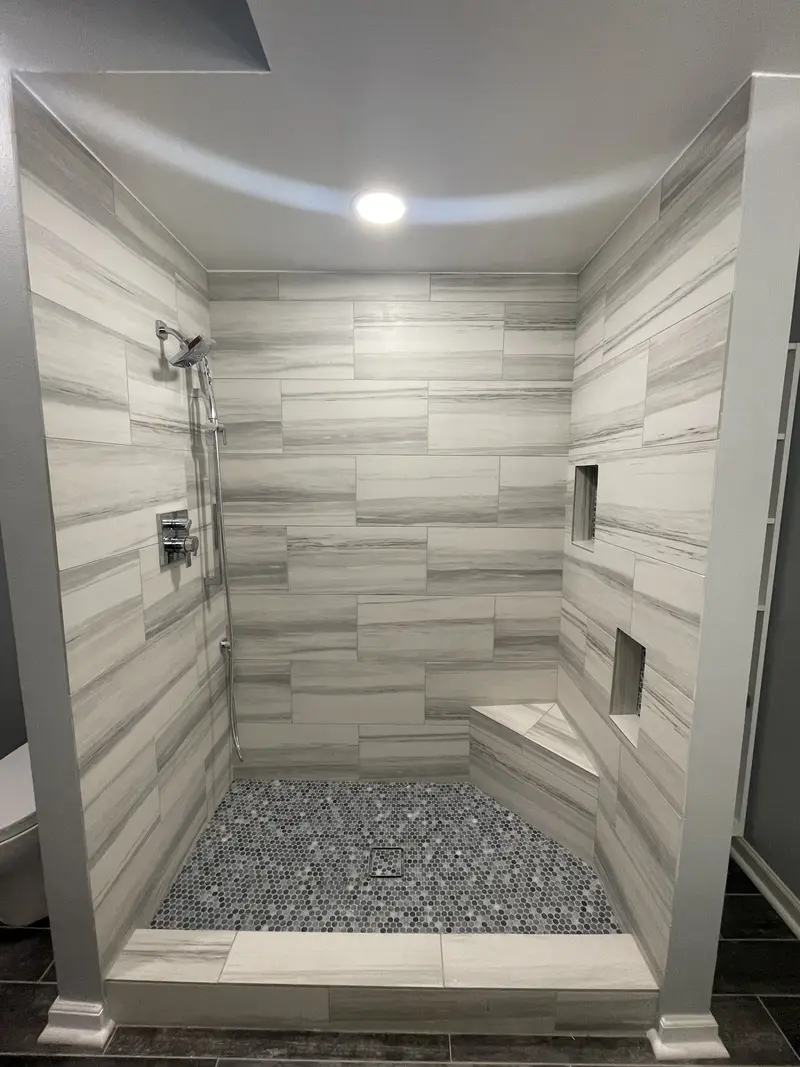Straight view into the open shower showing two recessed niches, a corner bench and chrome valves